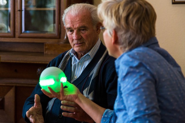 Pflegerin übergibt ichó einem Heimbewohner