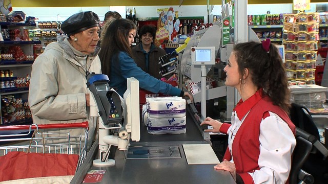 Ein Seniorin steht an der Supermarktkasse